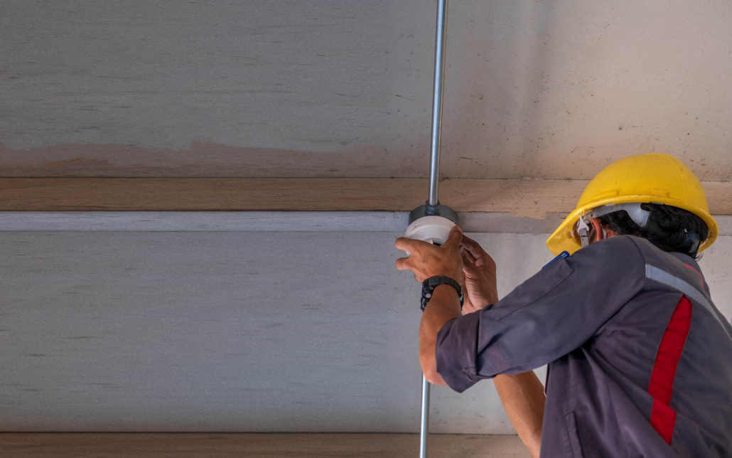 View Of A Person Installing Smoke Detector