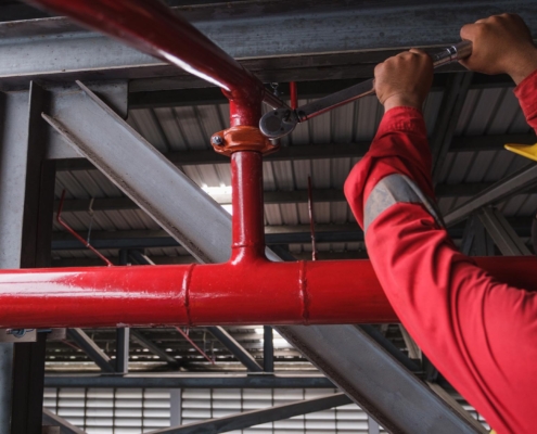 Worker Installing Fire Sprinkler System In Commercial Building