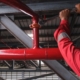 Worker Installing Fire Sprinkler System In Commercial Building